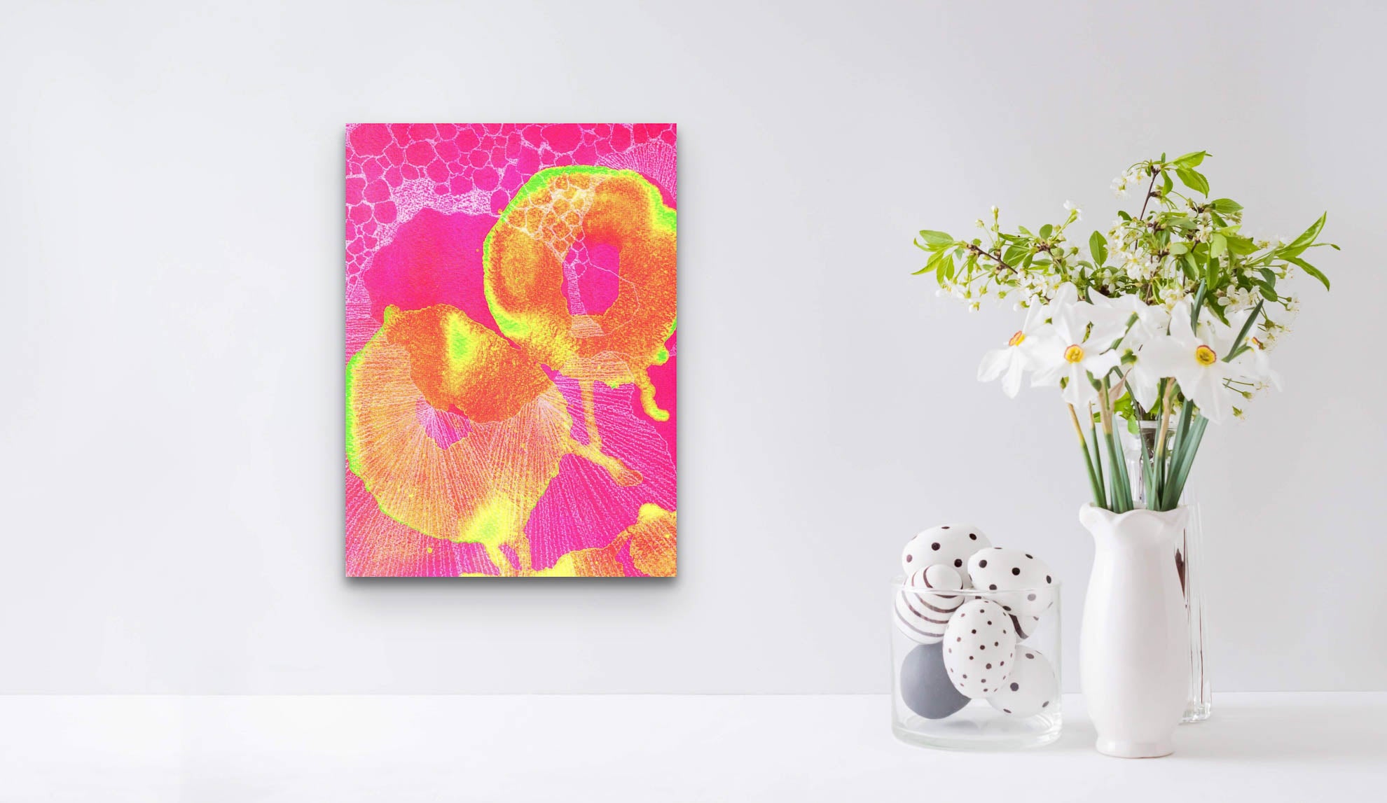 An abstract screen print in bright yellow, pink, green and white shown in a white home space background